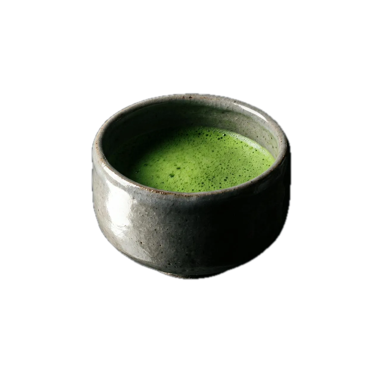 A speckled stoneware chawan of freshly whisked matcha, its surface still foamed, lit hard against black.